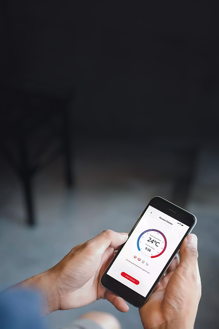 Smartphone in der Hand einer Person, darauf eine App zum Bedienen der Klimatisierung zu sehen.