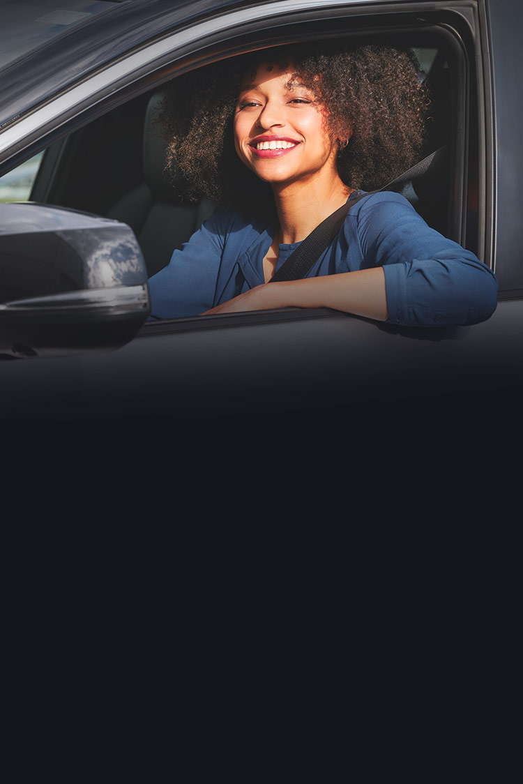Frau schaut lächelnd aus einem Auto